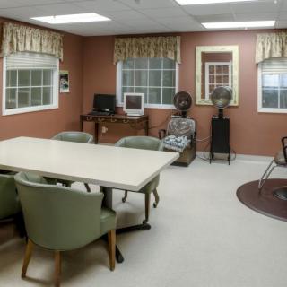 A spacious conference room with a table and chairs, featuring a computer desk and large windows.