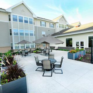 A sunny outdoor patio area with tables and chairs next to a modern building.
