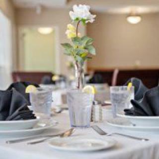 An elegantly set dining table with a flower centerpiece and neatly folded black napkins.