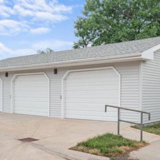 A double garage with white doors and a paved driveway under a cloudy sky.