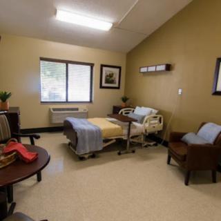 A hospital room with a single bed and seating area.