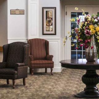 A well-decorated lobby with chairs and a flower arrangement on a table.