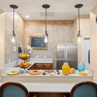 A modern kitchen with a breakfast bar, featuring pendant lights and stainless steel appliances.
