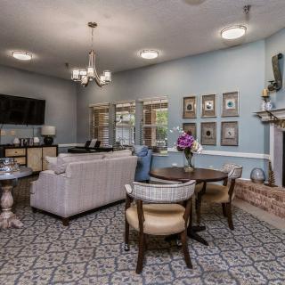 A modern living room with stylish furnishings, featuring a chandelier, fireplace, and decorative wall art.