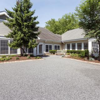 A spacious suburban house with a gravel driveway and surrounding greenery.
