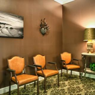 A cozy waiting room with orange chairs and elegant decor.