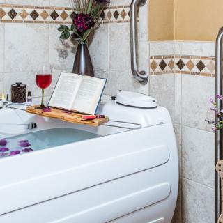 A luxurious bathtub setup with a book and wine, perfect for relaxation.