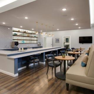 A modern cafe interior featuring a bar counter, seating area, and stylish lighting.
