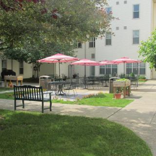 A peaceful courtyard with benches and outdoor seating under red umbrellas.