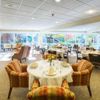 Elegant dining room with neatly arranged tables and chairs, set against large windows.