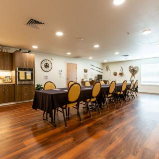 A well-decorated dining room with multiple chairs and tables, featuring a wooden floor and warm lighting.