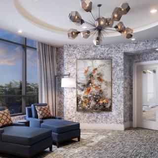 A modern living room featuring a stylish chandelier, luxurious blue seating, and a large piece of floral artwork under natural light from expansive windows.