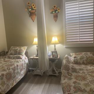 A cozy bedroom with twin beds, adorned with sunflower decor and illuminated by table lamps.
