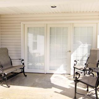 A cozy patio area with outdoor chairs and French doors, basking in the sunlight.