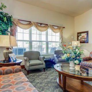 A cozy living room featuring comfortable seating, a round coffee table, and large windows with elegant curtains.