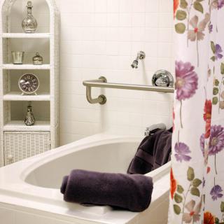 A bathroom featuring a bathtub with a floral shower curtain and neatly arranged towels.