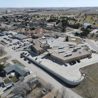 Aerial view of a building surrounded by a town and landscape.