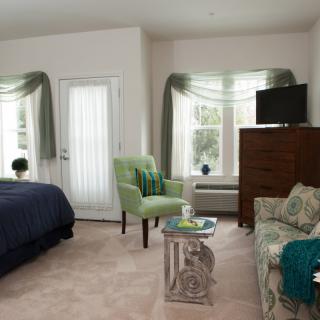 A cozy bedroom with a bed, seating area, and television.