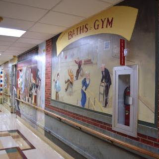 A vibrant mural depicting various sports activities in a gym hallway.