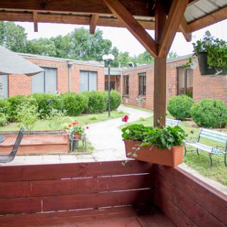 A serene garden view with a pathway leading through lush greenery and comfortable seating.