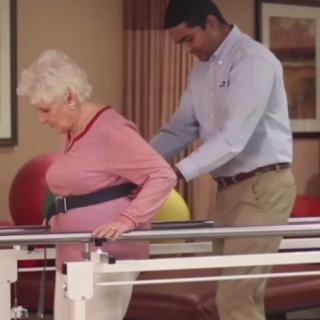 A healthcare professional assists an elderly woman with physical therapy exercises.