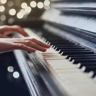 A person playing the piano with soft lighting in the background.