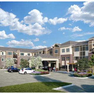 A modern residential building with a spacious parking lot and landscaped gardens under a partly cloudy sky.