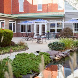 A serene garden patio with outdoor seating and a small pond surrounded by lush greenery.