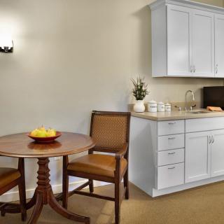 A cozy kitchenette with a small dining table and chairs beside white cabinets.