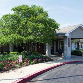A building entrance surrounded by trees and a landscaped garden.