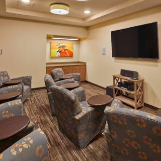 A cozy lounge area featuring comfortable chairs, a television for entertainment, and vibrant artwork on the walls.