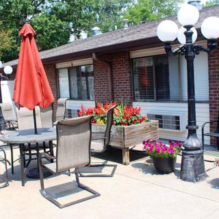 A cozy outdoor patio area with a table, chairs, and vibrant flowers.