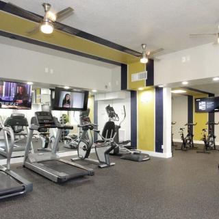 A modern gym equipped with treadmills, exercise bikes, and televisions.