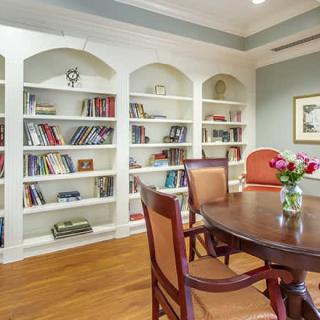 A cozy library interior with bookshelves and a dining table arrangement.