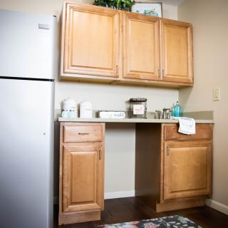 A compact kitchen area with wooden cabinets, a sink, and a refrigerator.