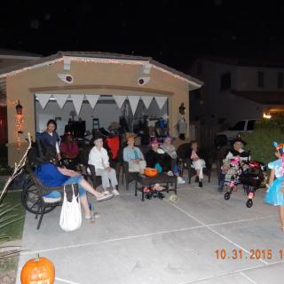 A Halloween gathering with people in costumes outside a decorated home at night.