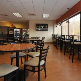 An empty cafeteria with tables and chairs arranged near large windows.