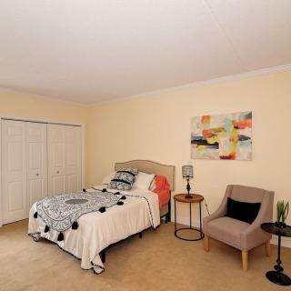 A cozy bedroom with a single bed, modern artwork, and a comfortable chair.