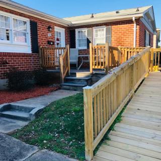 A brick house with a wooden accessibility ramp leading to the front entrance.