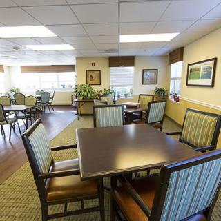 A spacious and well-lit dining area with tables and chairs, decorated with plants and artwork.