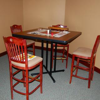 A small dining setup with a square table and four wooden bar stools.