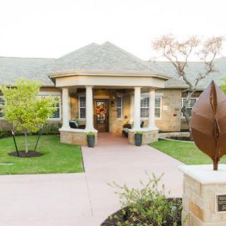 Elegant building entrance with a garden and sculpture.