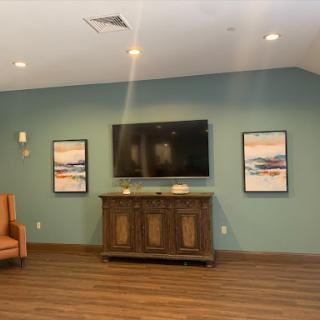 A cozy living room setup featuring a television, decorative art pieces, and wooden flooring.