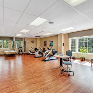A spacious exercise room with gym equipment and bright natural lighting from large windows.