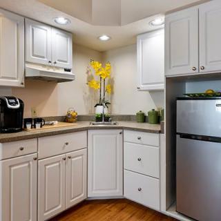 A compact modern kitchen with white cabinets and sleek appliances.