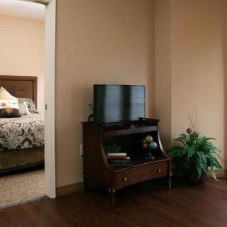 A cozy living space with a television and furniture, featuring a doorway leading to a bedroom.