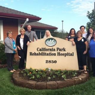 A group of people standing in front of the California Park Rehabilitation Hospital sign.