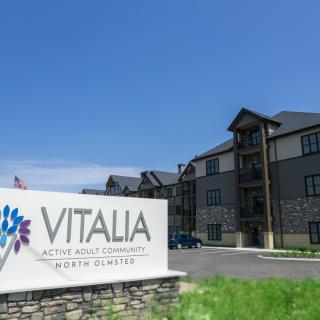 An exterior view of the VITALIA active adult community apartment complex with a prominent sign in the foreground.