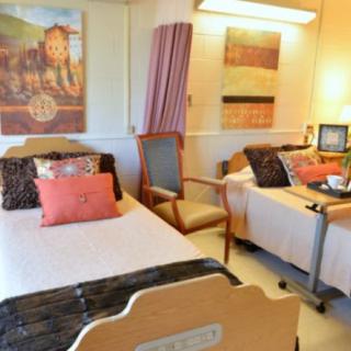A well-decorated hospital room with two beds, featuring cozy decor and accessibility features.