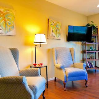 A cozy living room with comfortable armchairs, warm lighting, and decorative wall art.